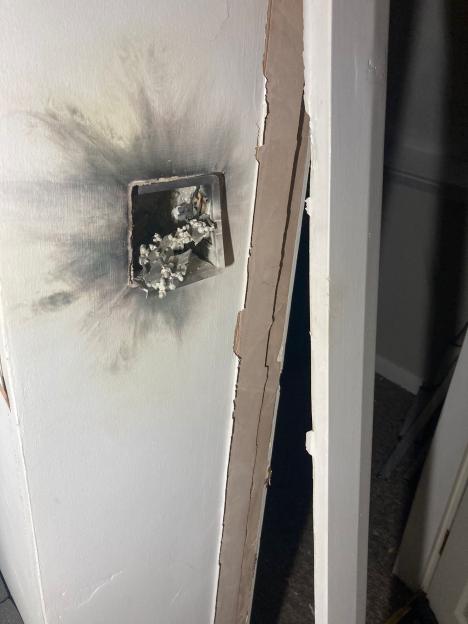 Charred drywall and melted plastic from an electrical outlet damaged by lightning.