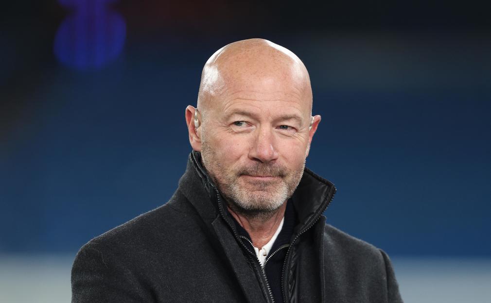 Television host Alan Shearer in a dark coat, looking on during a UEFA Champions League match.