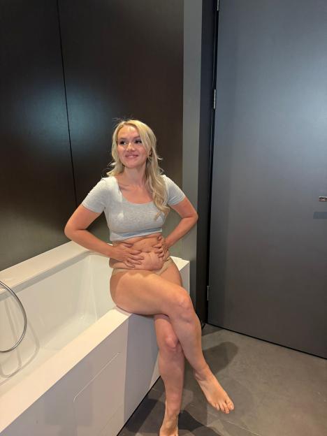 Melissa Suffield smiling while sitting on a bathtub, holding her stomach, as part of her glamorous transformation for the TV Baftas.