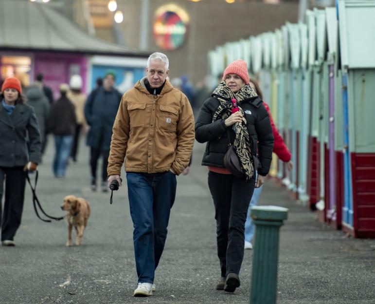 Zoe Ball and Mat Weekes walk together along a seaside promenade.