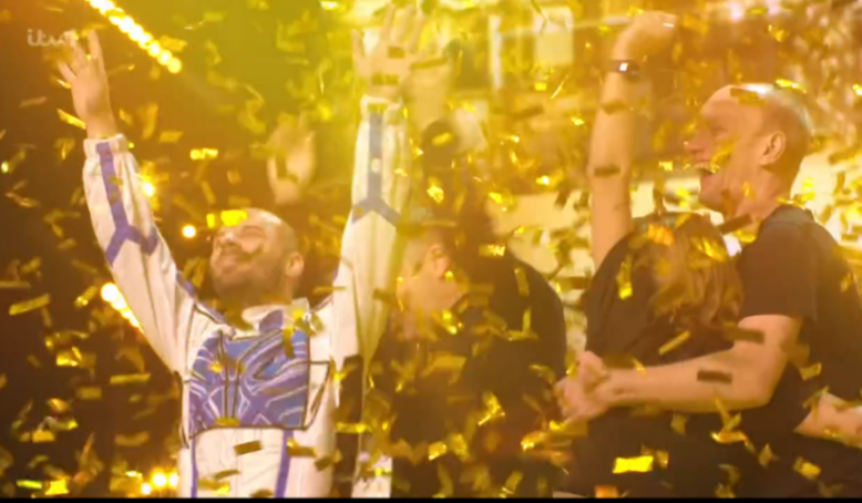 Performers and judges celebrating under a shower of golden confetti.