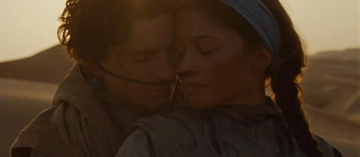 Timothée Chalamet and Zendaya embrace against a desert backdrop in a scene from Dune: Part Two.