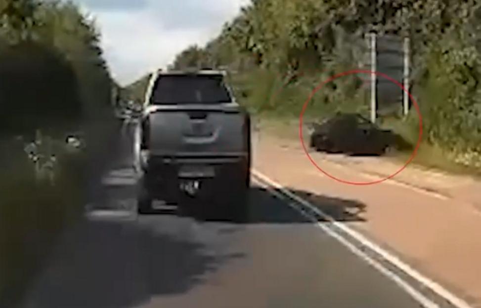 Footage of Mariusz's car crashing, circled in red, next to a black pickup truck on a rural road.