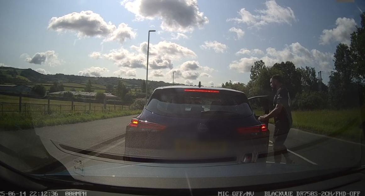 A man confronting another driver on the road from a dashcam perspective.