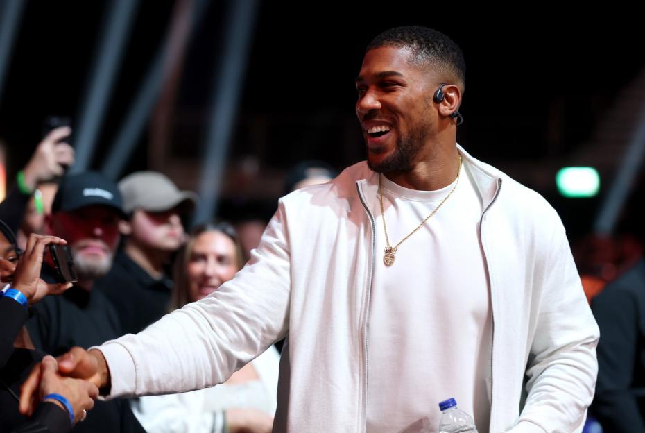 Anthony Joshua shaking hands with fans at a boxing event.