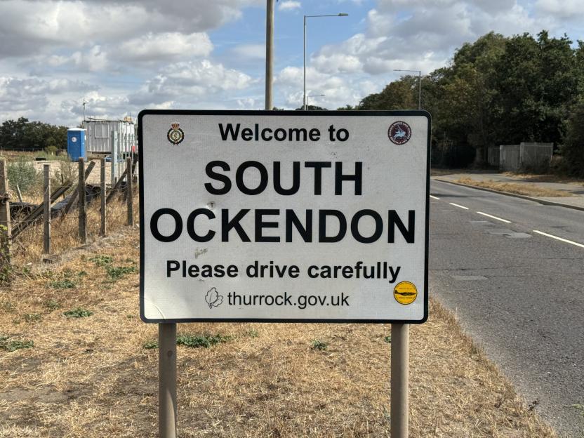 Welcome to South Ockendon sign on a street next to a travelers' site.