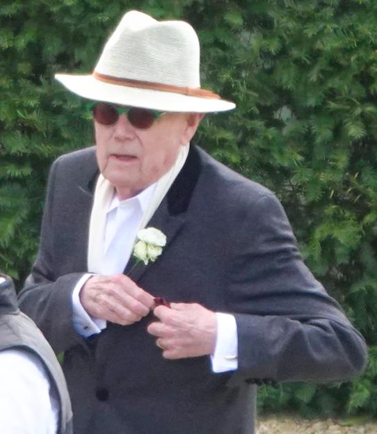 Michael Whitehall, dressed in a hat and suit with a boutonniere, is assisted out of a black car at Euridge Manor.