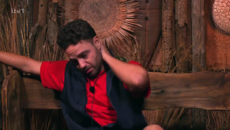 Adam Thomas looking upset and tearful on a wooden bench.