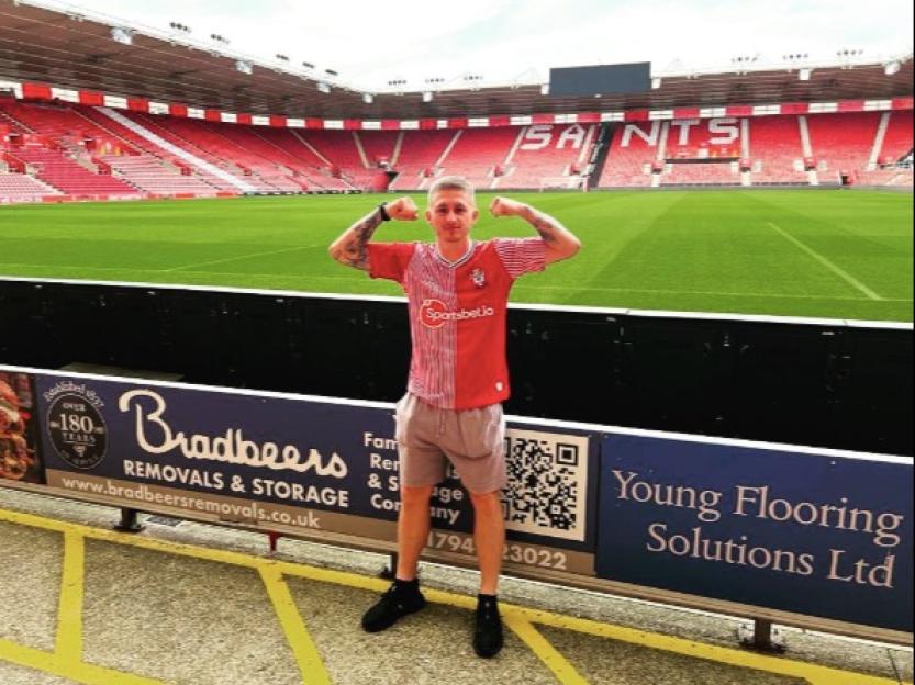 A man in a red and white striped jersey flexing his biceps in a stadium.
