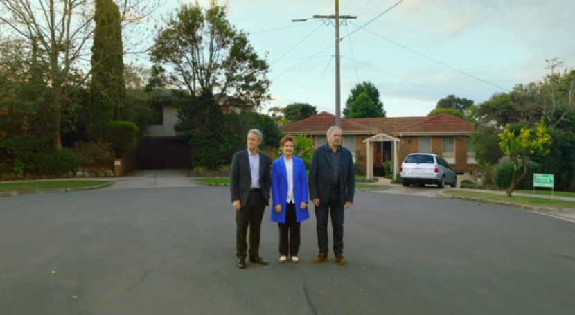 Three actors stand in the street in front of houses in the final scene of the Neighbours TV show.