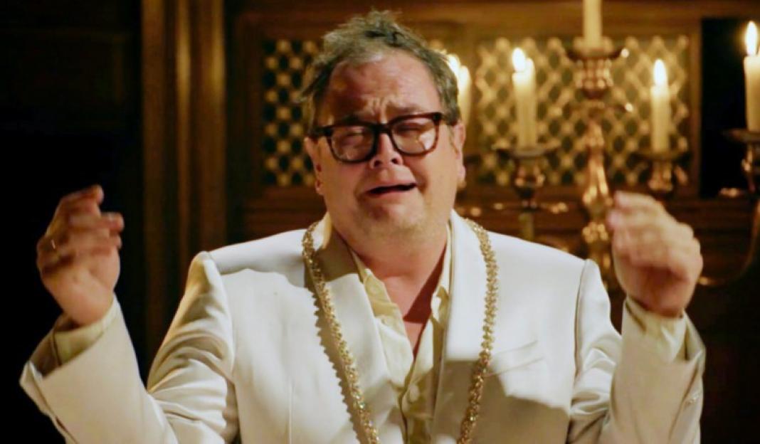 Alan Carr crying with his hands raised.