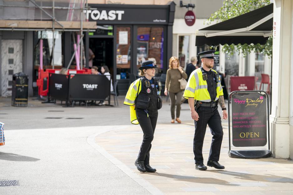 Two security guards, a man and a woman in uniforms, patrol a street in Braintree, Essex.