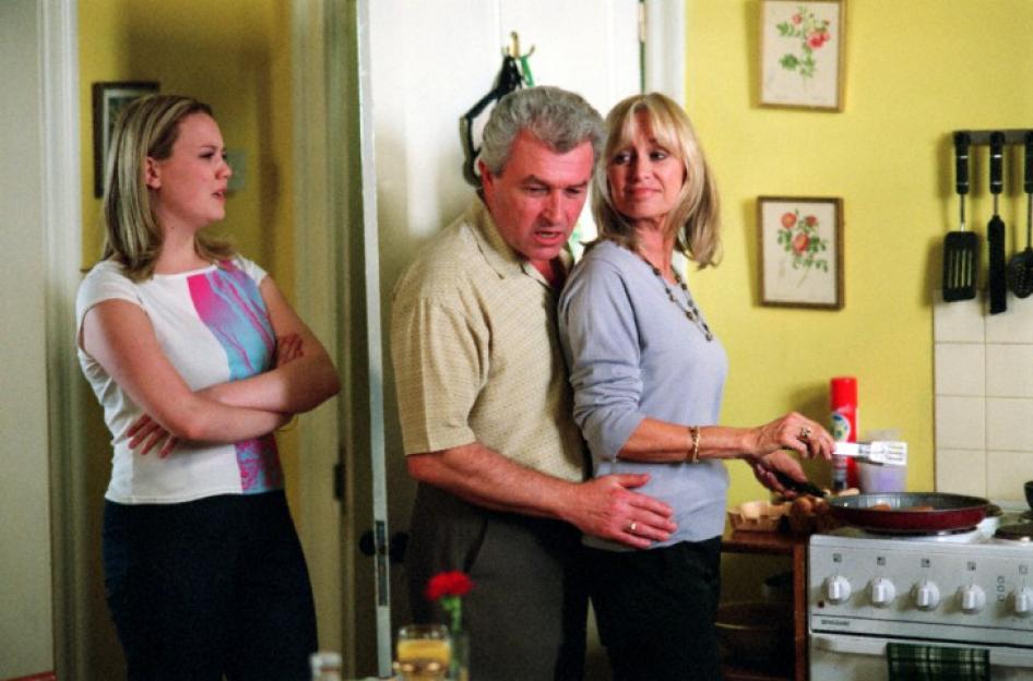 A young woman watches a couple from a distance.