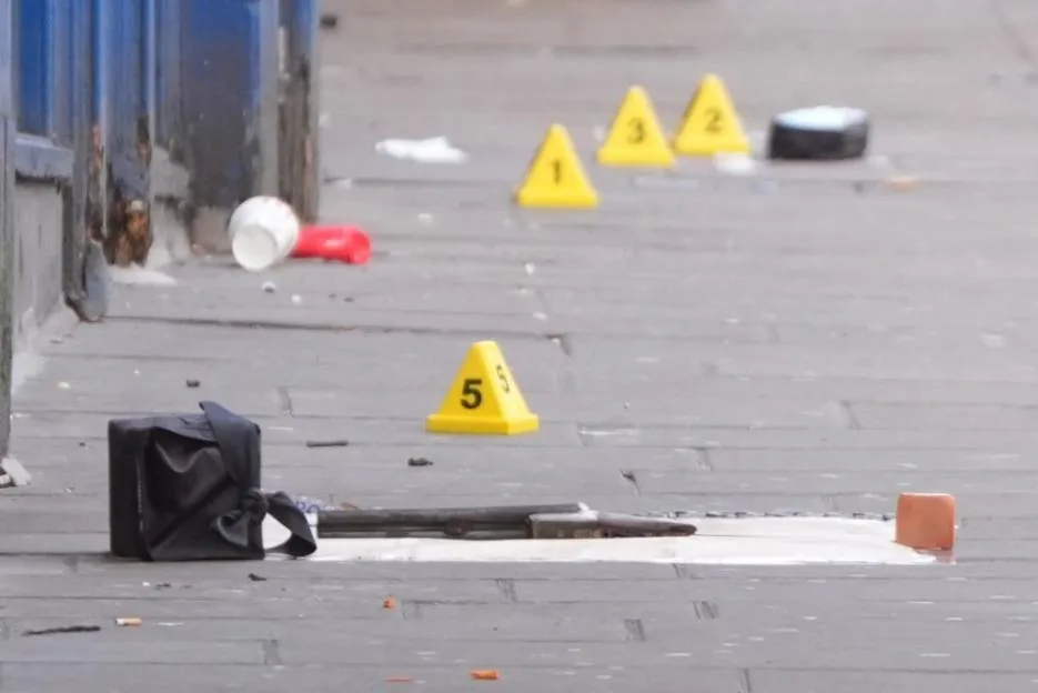 Crime scene markers, a bag, and a firearm on a street pavement.