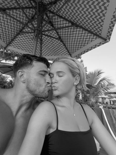 A black and white photo of Molly-Mae Hague and Tommy Fury kissing under a patterned umbrella.