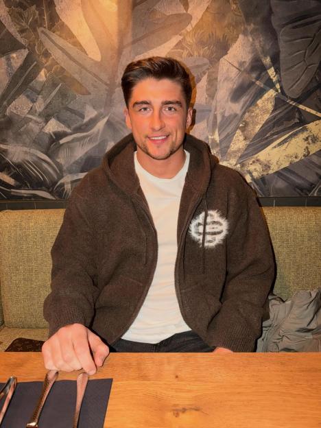 Love Island star Scott van-der-Sluis sitting at a table.