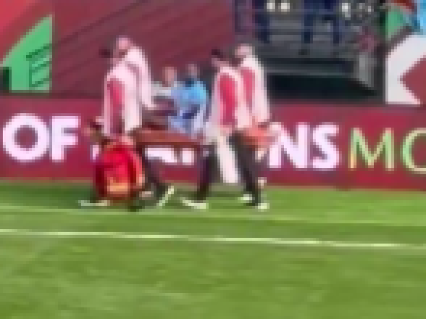 Medical staff carrying an injured player on a stretcher off the field during a game.