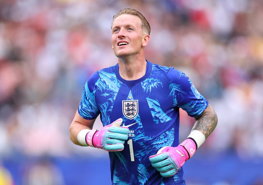 England player Jordan Pickford in a blue and white patterned jersey and pink and blue gloves.