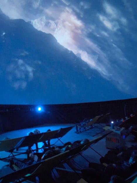 People seated in a planetarium watching a celestial projection.