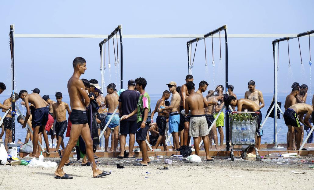 Migrants bathing at communal showers in a refugee camp.