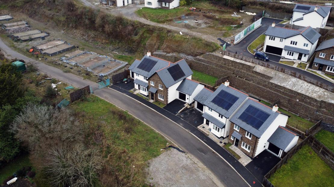 An aerial view of a new-build housing estate with some completed houses and others still under construction.