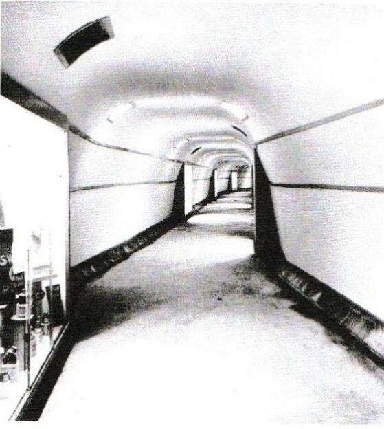 A long, brightly lit tunnel with display cases on the left.