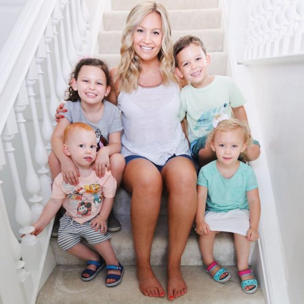 A woman sitting on stairs with four children, a boy and three girls.
