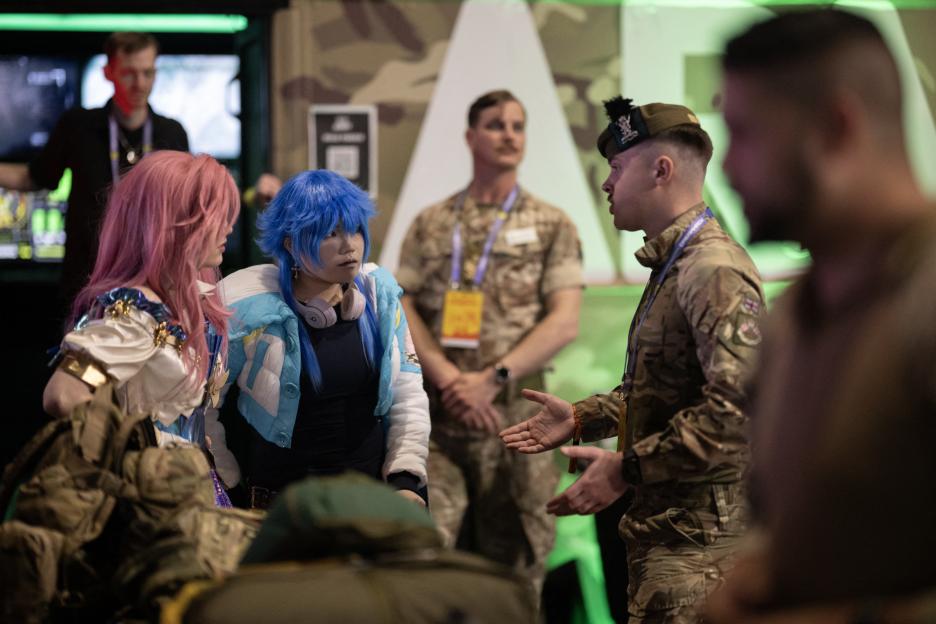 A member of the British Army's public engagement team speaks with cosplayers at DreamHack 2026 gaming convention.