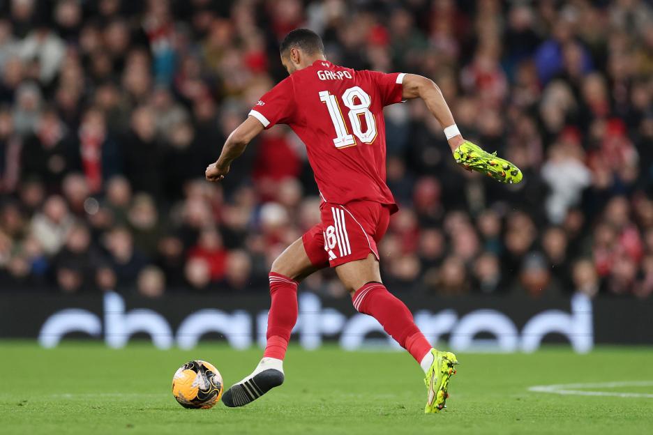 Cody Gakpo of Liverpool carries his right boot whilst running during a soccer match.