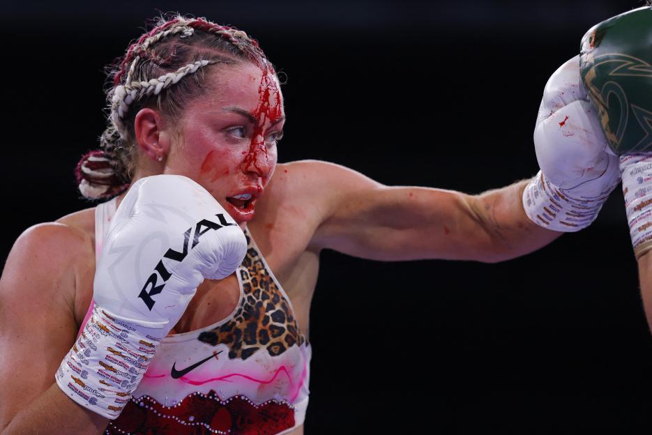 Ebonie Cotton boxing with blood on her face, wearing white and leopard print, throwing a punch.
