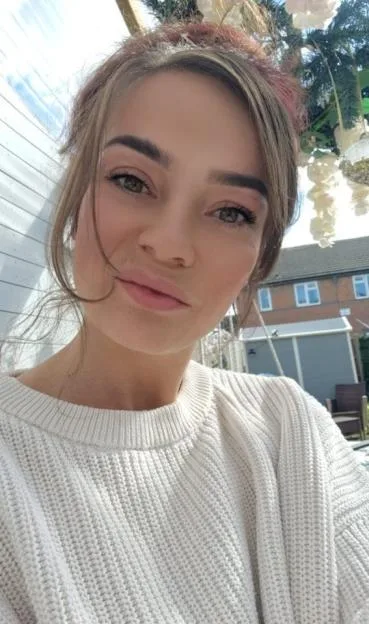 Danielle Thomas wearing a white knitted sweater outdoors.