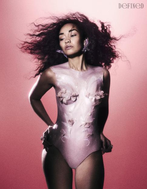 Leigh-Anne Pinnock wearing a pink bodysuit with floral accents and butterfly earrings, with hair blowing.