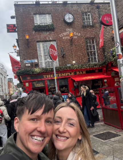 Two women smiling for a selfie in front of The Temple Bar in Dublin.