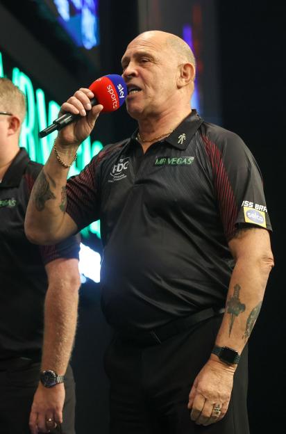 PDC referee Russ Bray speaking into a Sky Sports microphone.