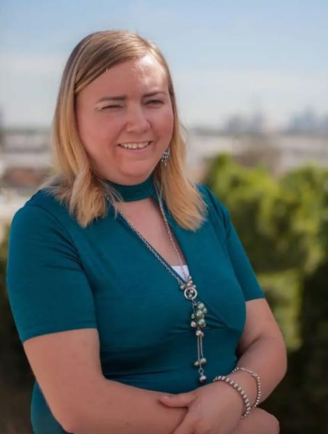 Briell Decker wearing a teal top and a long necklace.
