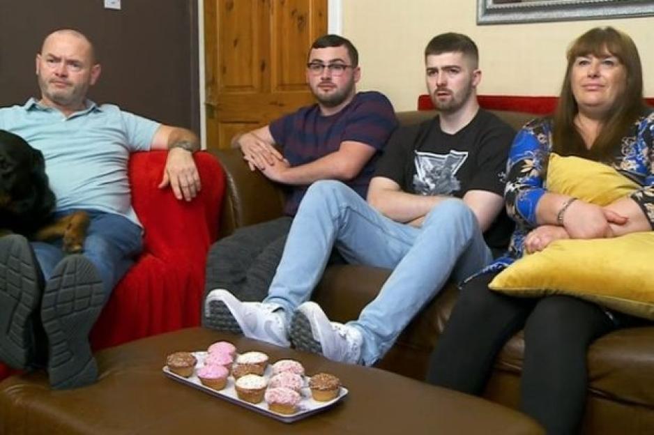 The Malone family from Gogglebox sitting on a sofa with cupcakes on a tray in front of them.
