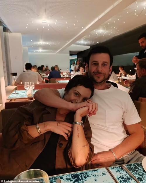 Domenica Calarco and Jarod Bogunovich smiling, with Domenica leaning on Jarod's shoulder at a restaurant.