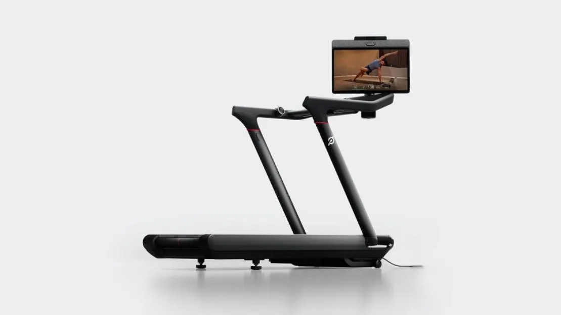 A black Peloton Tread with a screen displaying a person doing a side plank.