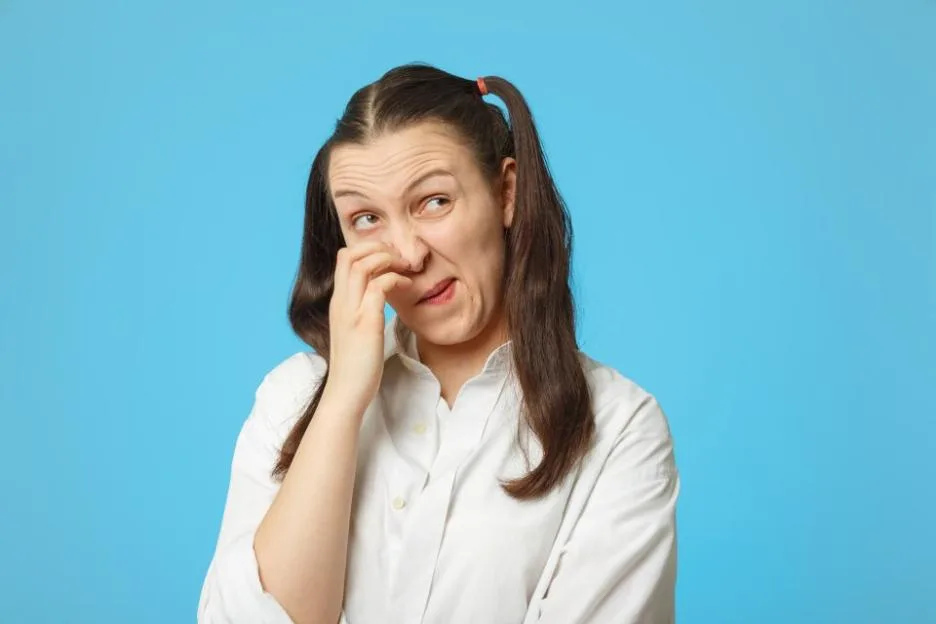 A thoughtful girl scratching her nose against a blue background.