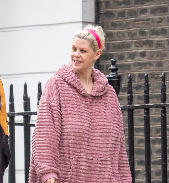 Fifi Geldof smiling while wearing a pink textured top and a pink headband, holding a cigarette.