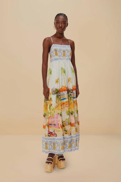 A woman wearing a maxi dress with a colorful tropical village print and platform sandals.