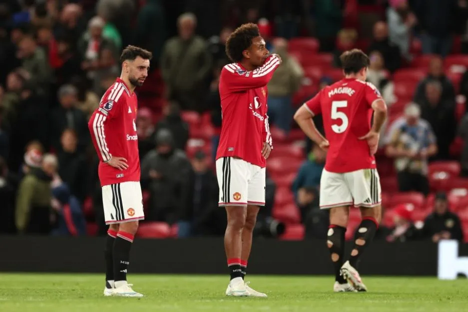 Dejected Manchester United players on the pitch after a match.