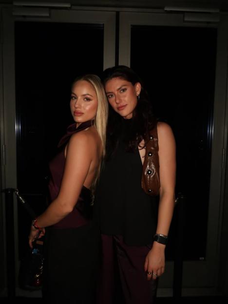 Two women posing together in dark clothing.