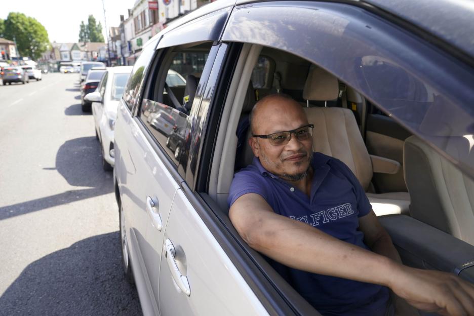 Mohammed Uddin, 52, in a blue polo shirt and glasses, sitting in his car on a street known for parking issues.