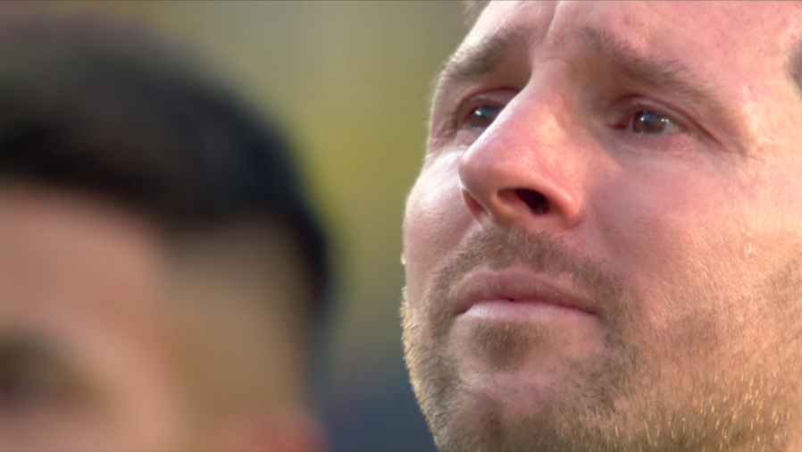 A man with a beard and mustache cries, a tear visible on his cheek.
