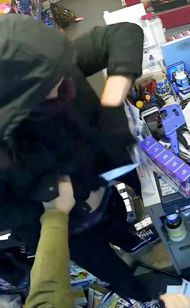 CCTV footage of a robber in a balaclava holding a knife and a shopkeeper holding a walking stick.
