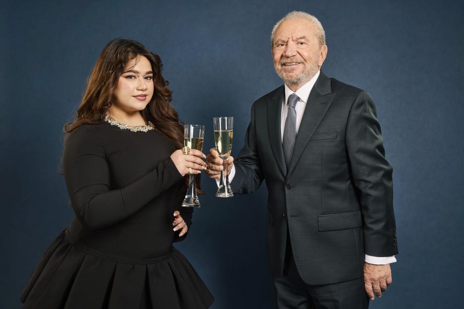 Karishma Vijay and Lord Sugar clinking champagne glasses.