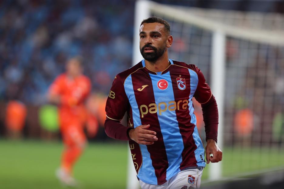 A Trabzonspor player in a maroon and light blue striped jersey on the field during a UEFA Europa League match.