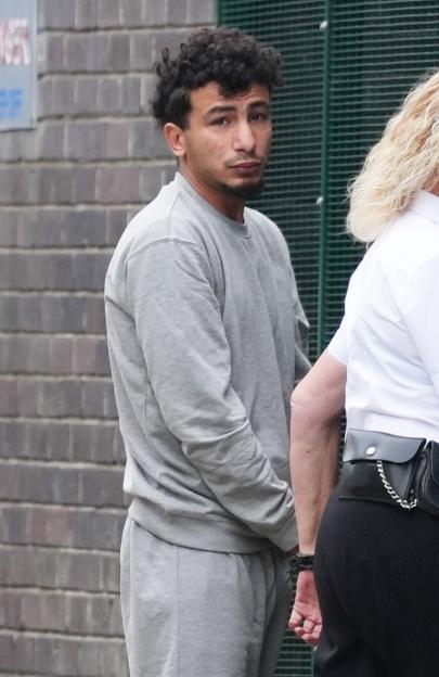 Ibrahim Alshafe, wearing a gray tracksuit, being escorted by an officer.