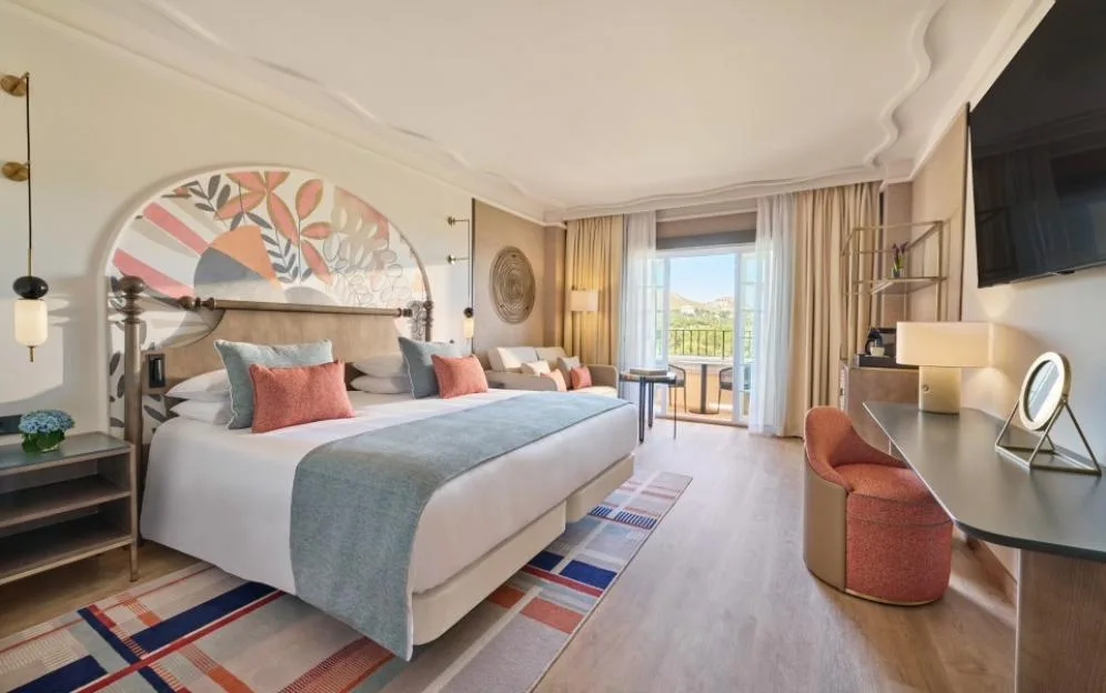 Luxurious hotel bedroom with a large bed, balcony view, and modern furnishings.